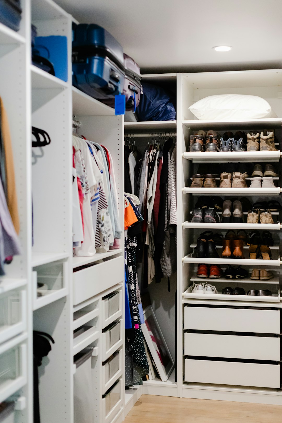 A modern, white closet with open shelving, drawers, and a rack for clothes u0026 footwears.